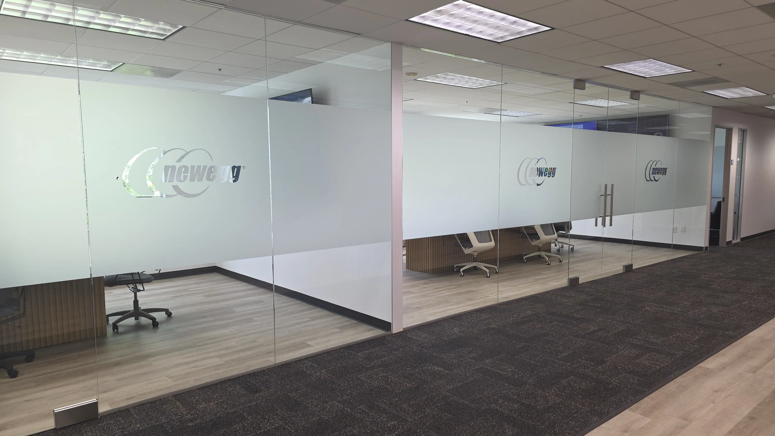 Newegg conference rooms with glass walls, frosted privacy bands, and double glass doors.
