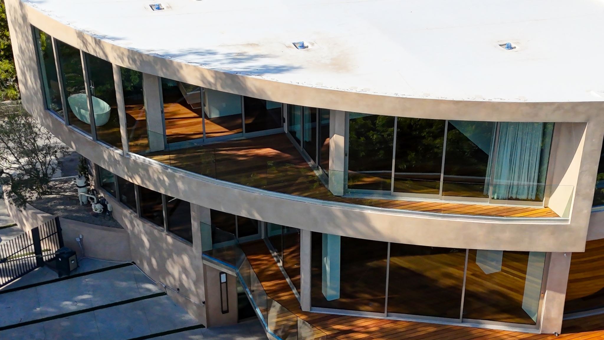 The Brentwood residence from above: two floors of curved glass wrapping the canyon-facing elevation.