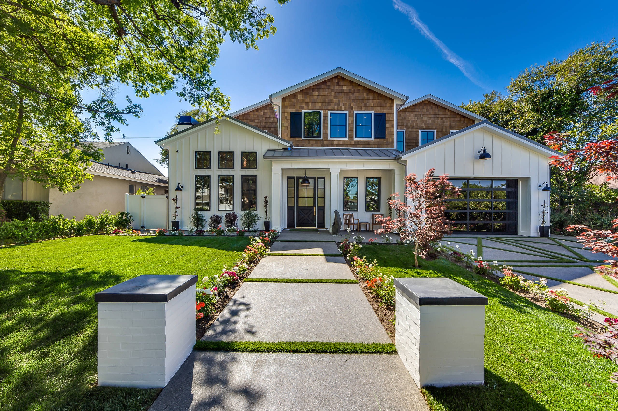 A white gabled residence in Encino with a shingled gable and a lawn, photographed in afternoon light.