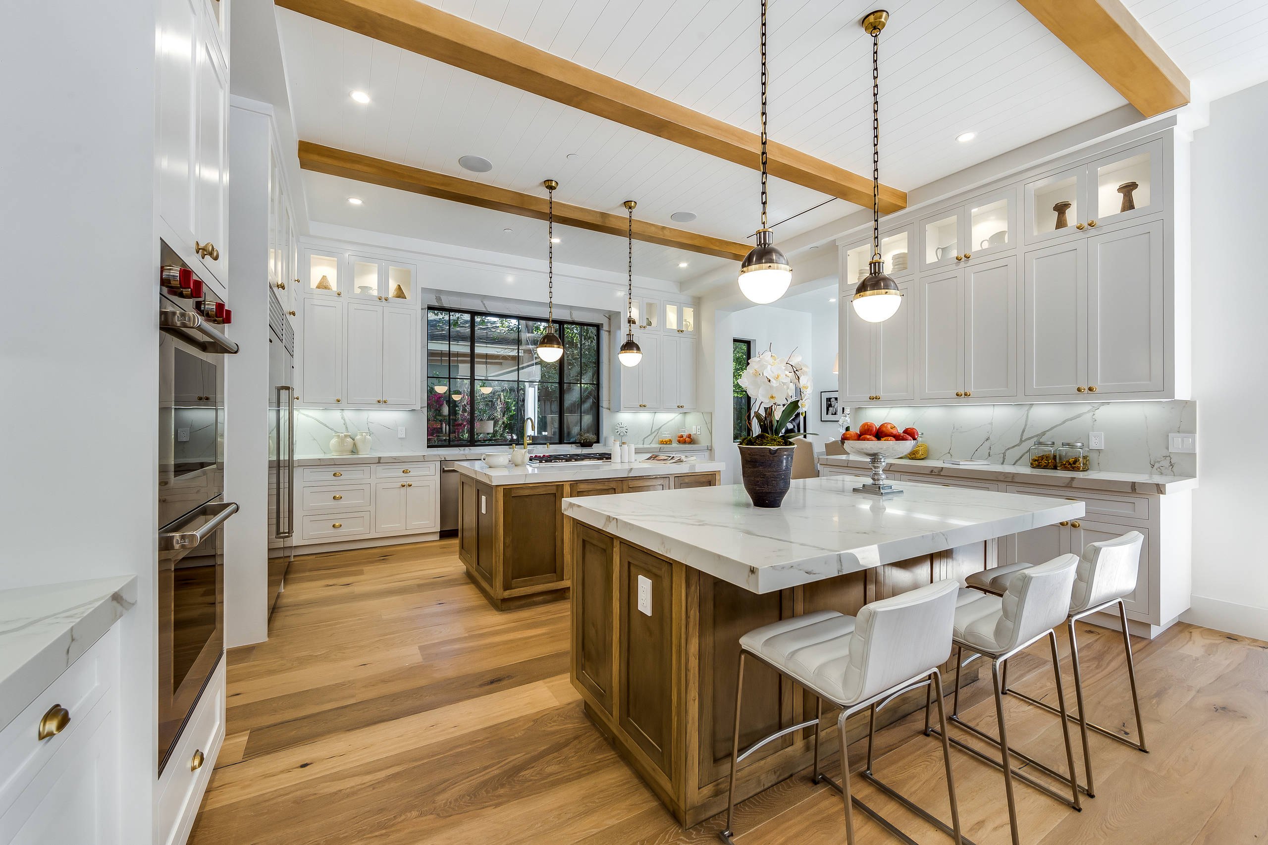 The Encino kitchen: a marble island beneath exposed beams and pendant lights.