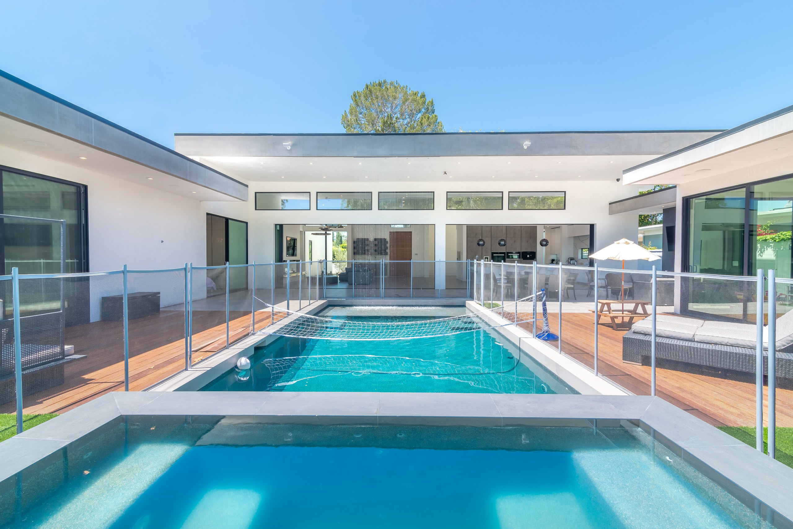 A white, flat-roofed modern residence in Sherman Oaks wrapped around a courtyard pool, with full-height glass on every side.